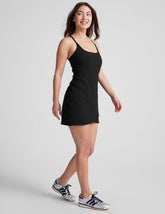black ribbed mini length dress with a soft scoop front neckline, back strap cross-over detail, overlapping front hem detail, and interior shorts with pockets.